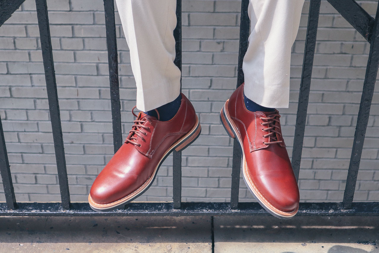 closeup of man wearing brown shoes sitting on a fence