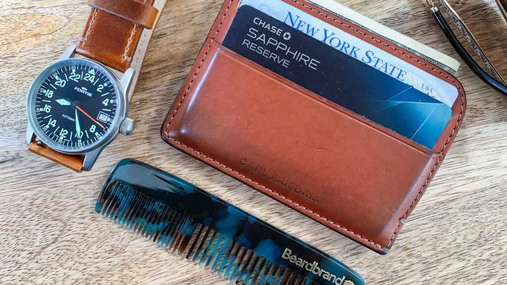 overhead shot of men's accessories, cardholder wallet, wristwatch, and pocket comb