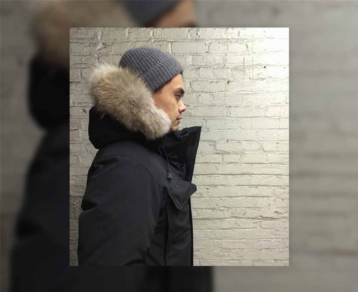 man facing right and wearing black parka with fur hood