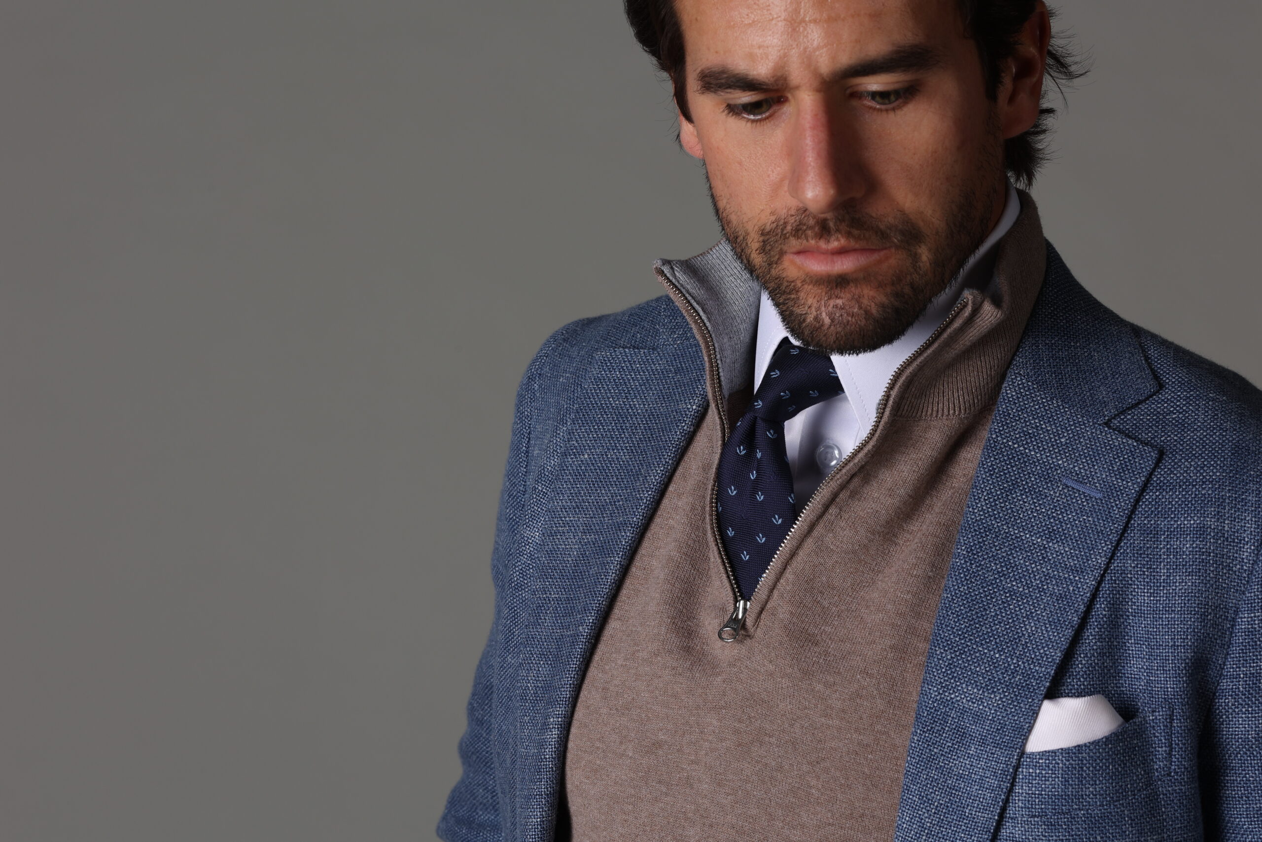 closeup of man in white shirt and tie, brown seater and blue suit jacket