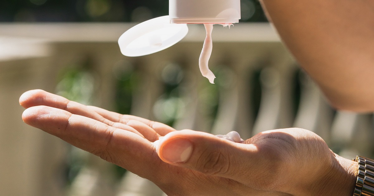 hand cream being squeezed out of bottle onto hand