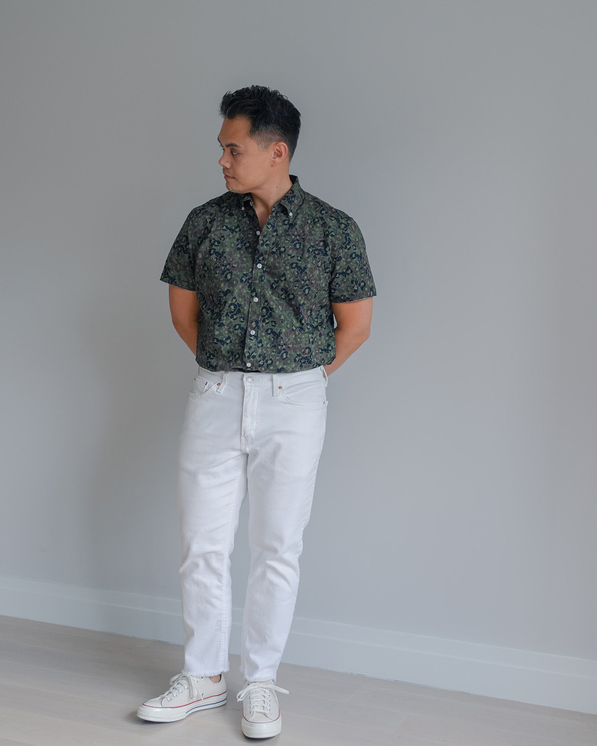 man in white denim jeans and a green camo style short sleeve button up shirt