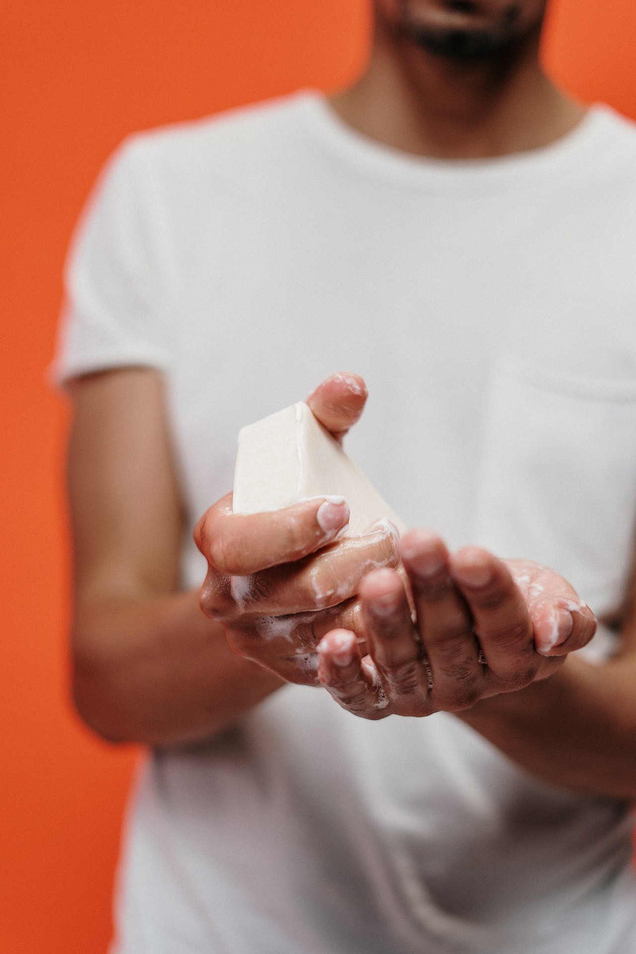 man in white tshirt washing hands with soap bar