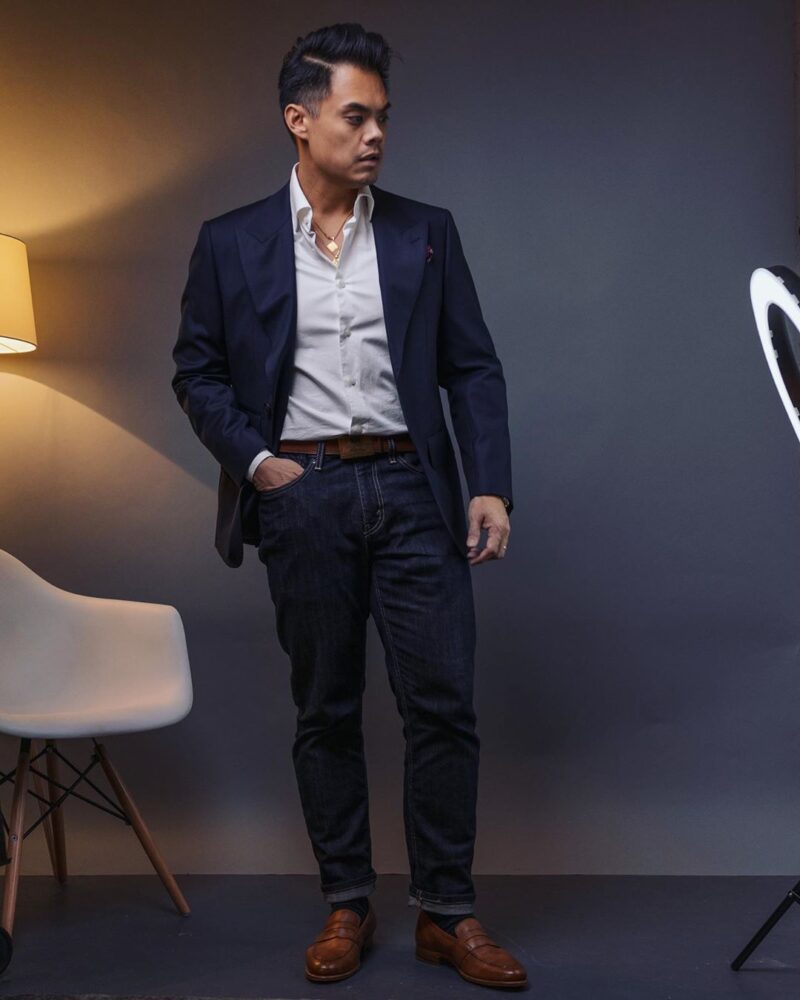man in navy jacket, white shirt, dark blue jeans, and brown loafers