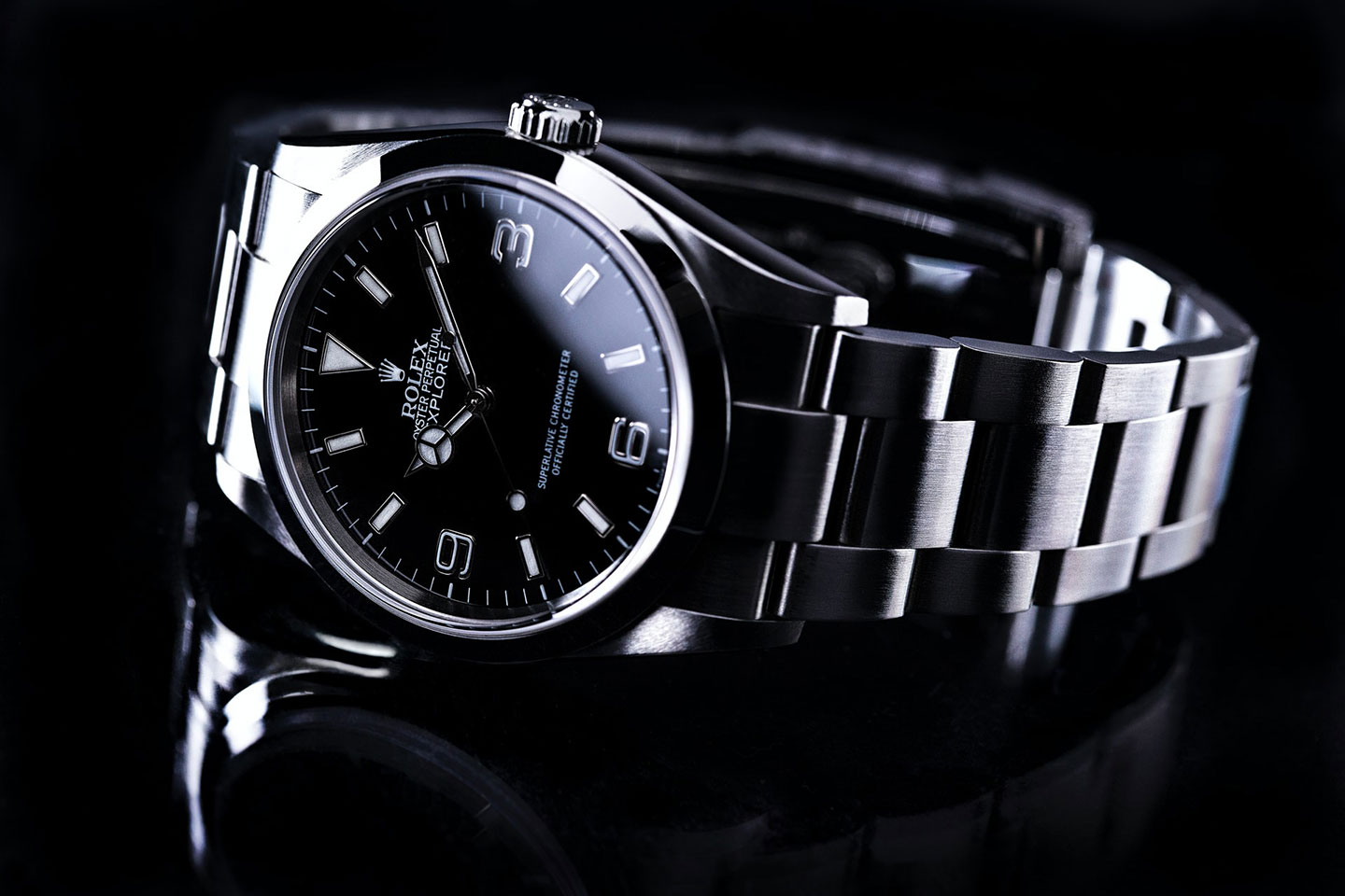 black dial rolex explorer on black reflective table closeup