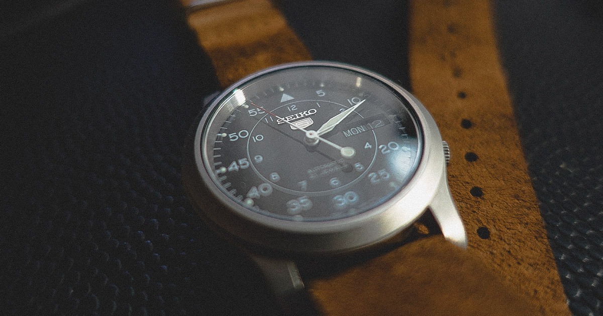 closeup of seiko 5 watch black dial with brown leather strap